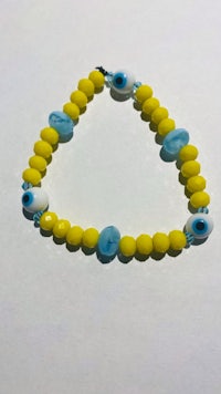 a yellow and blue evil eye bracelet on a white surface