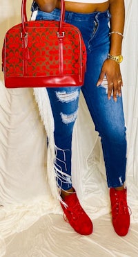 a woman in ripped jeans holding a red purse