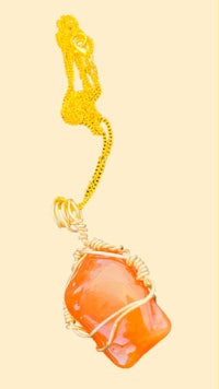 an orange stone pendant on a gold chain