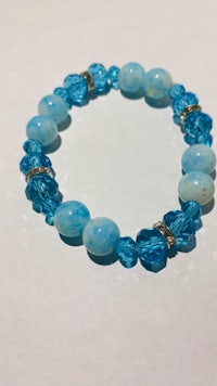 a bracelet with blue beads and crystals on a white surface