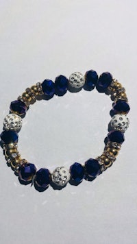 a bracelet with blue and gold beads on a white surface