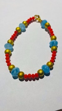 a bracelet with red, blue and gold beads